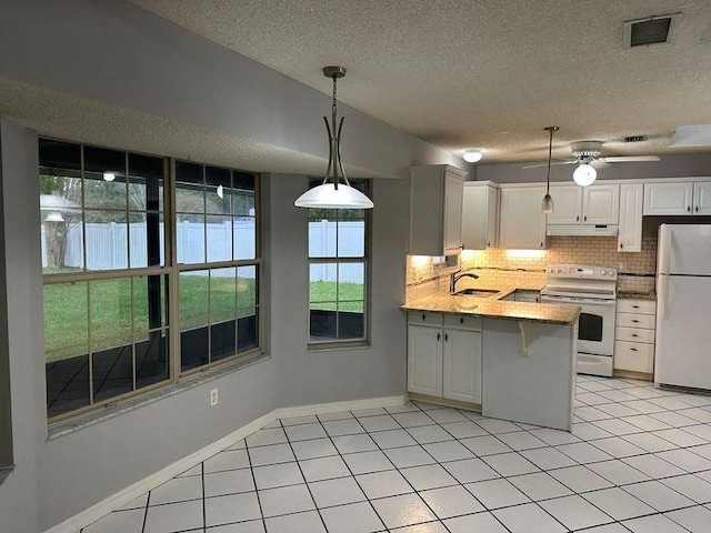 kitchen featuring white appliances, sink, kitchen peninsula, decorative light fixtures, and white cabinetry