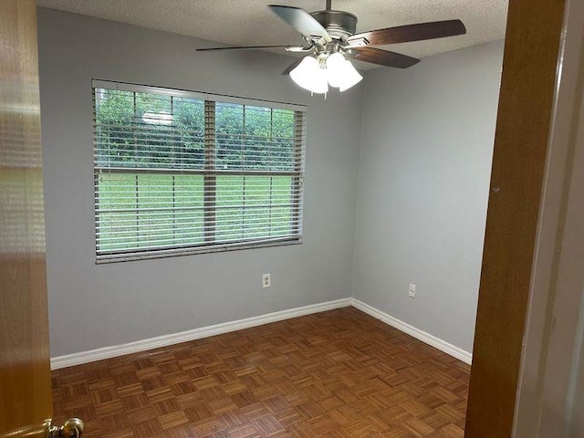 unfurnished room with a textured ceiling, ceiling fan, and dark parquet floors