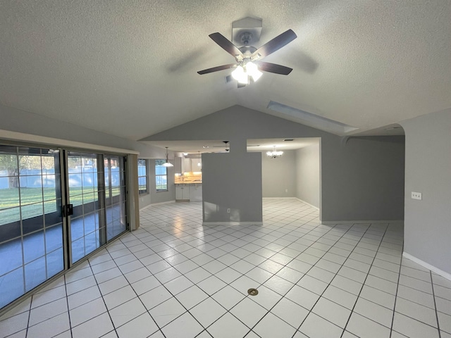 unfurnished room featuring ceiling fan with notable chandelier, light tile patterned floors, a textured ceiling, and lofted ceiling