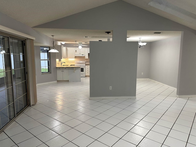 interior space with sink, vaulted ceiling, a textured ceiling, a notable chandelier, and light tile patterned flooring