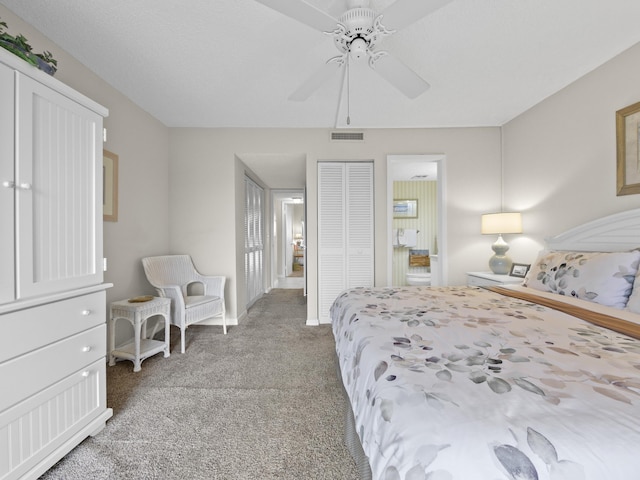 bedroom featuring a ceiling fan, light colored carpet, visible vents, and ensuite bathroom