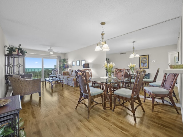 dining space featuring ceiling fan, light wood-style floors, visible vents, and a textured ceiling