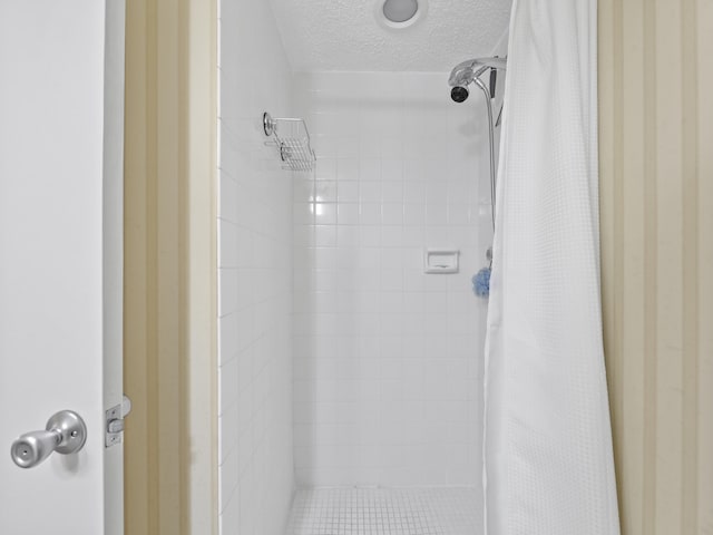 bathroom featuring a textured ceiling and a tile shower