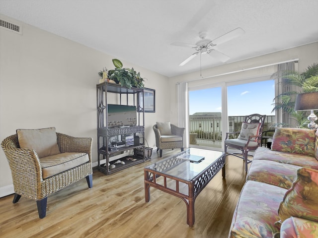 living area with visible vents, baseboards, light wood-style floors, and ceiling fan