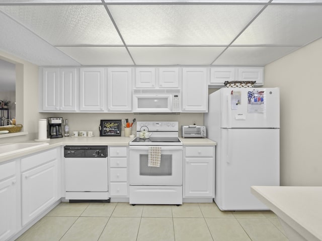 kitchen with light tile patterned floors, white appliances, white cabinetry, and light countertops