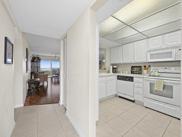 kitchen with white cabinetry, white appliances, light tile patterned flooring, and light countertops