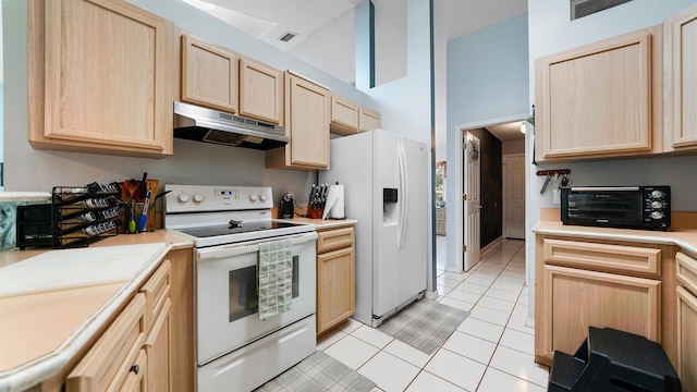 kitchen with light brown cabinets, light tile patterned flooring, white appliances, and high vaulted ceiling