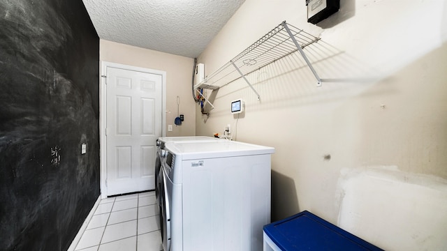 washroom with washing machine and clothes dryer, light tile patterned floors, and a textured ceiling