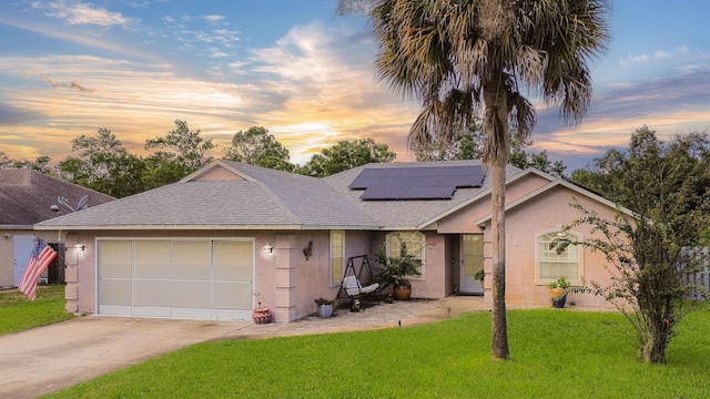 ranch-style house featuring a lawn, a garage, and solar panels