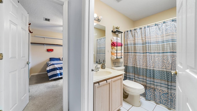 bathroom featuring vanity, tile patterned flooring, toilet, a textured ceiling, and walk in shower