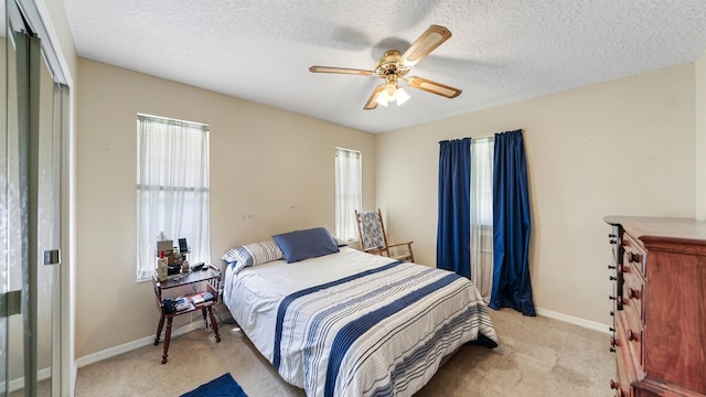 bedroom featuring ceiling fan, a closet, light carpet, and a textured ceiling