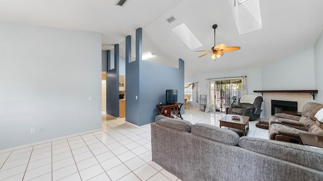 tiled living room featuring a skylight, ceiling fan, high vaulted ceiling, and a tiled fireplace