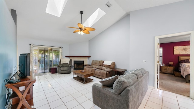 living room with a skylight, high vaulted ceiling, ceiling fan, and light tile patterned flooring