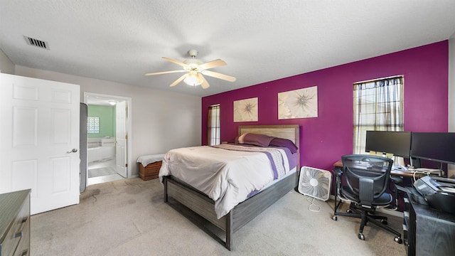 bedroom with a textured ceiling, ceiling fan, light carpet, and connected bathroom