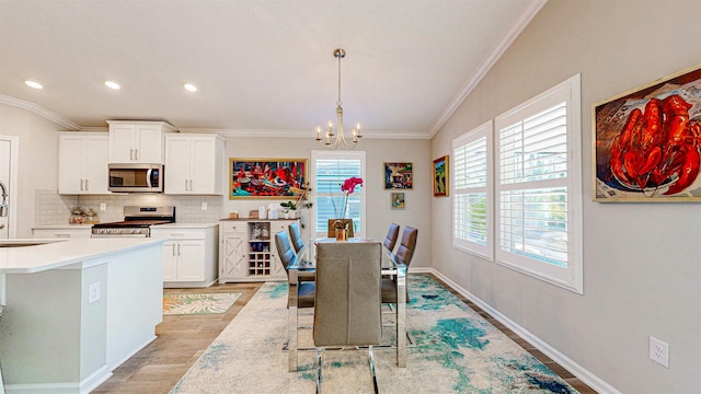 dining room featuring a notable chandelier, ornamental molding, sink, and light wood-type flooring