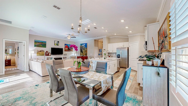 dining space featuring crown molding, sink, ceiling fan with notable chandelier, and light hardwood / wood-style floors