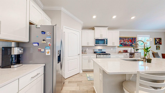 kitchen with light stone countertops, appliances with stainless steel finishes, sink, and white cabinets