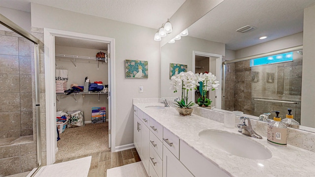 bathroom featuring vanity, wood-type flooring, a textured ceiling, and walk in shower