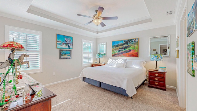 carpeted bedroom featuring a tray ceiling, ornamental molding, and ceiling fan