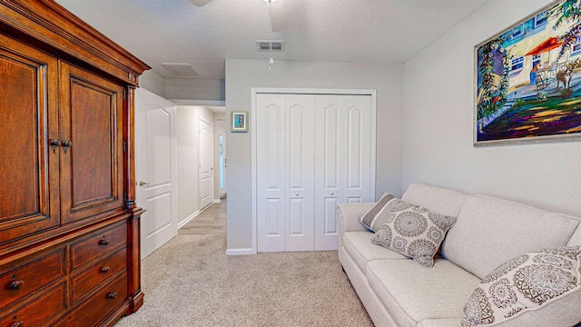 sitting room with ceiling fan, light carpet, and a textured ceiling