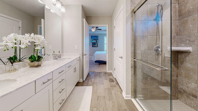 bathroom featuring vanity, wood-type flooring, a shower with shower door, and ceiling fan