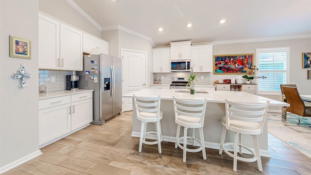 kitchen with sink, a breakfast bar, white cabinetry, a kitchen island with sink, and stainless steel appliances