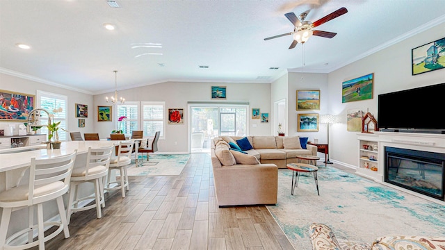 living room featuring crown molding, lofted ceiling, ceiling fan with notable chandelier, and light hardwood / wood-style floors