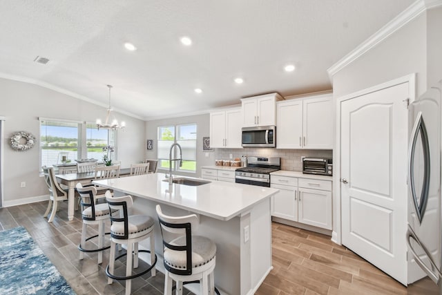 100 Dove Tree Ln, Saint Augustine, FL 32095 - kitchen with stainless steel appliances, vaulted ceiling, a center island with sink, crown molding, and tasteful backsplash