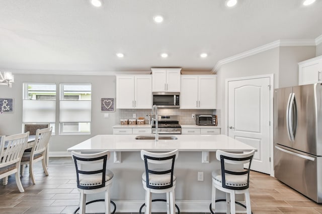 100 Dove Tree Ln, Saint Augustine, FL 32095 - kitchen with appliances with stainless steel finishes, light countertops, a center island with sink, decorative backsplash, and crown molding