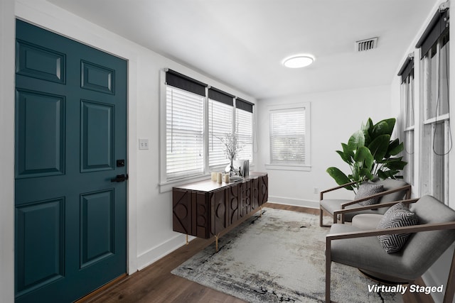foyer entrance with dark wood-style floors, baseboards, and visible vents