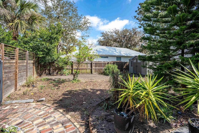 view of yard with a fenced backyard, an outdoor structure, and a storage unit