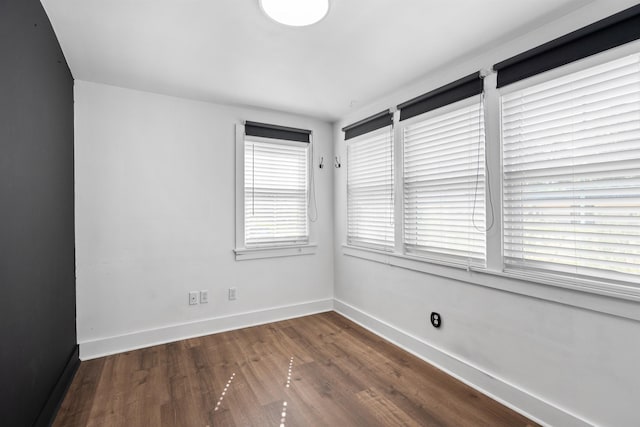 spare room featuring baseboards and wood finished floors