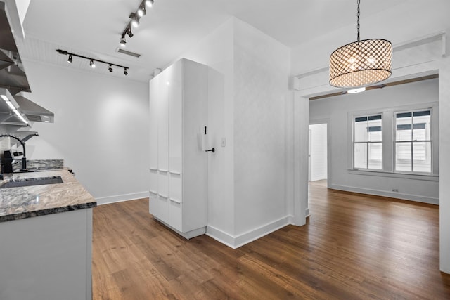 kitchen featuring open shelves, wood finished floors, a sink, stone countertops, and baseboards