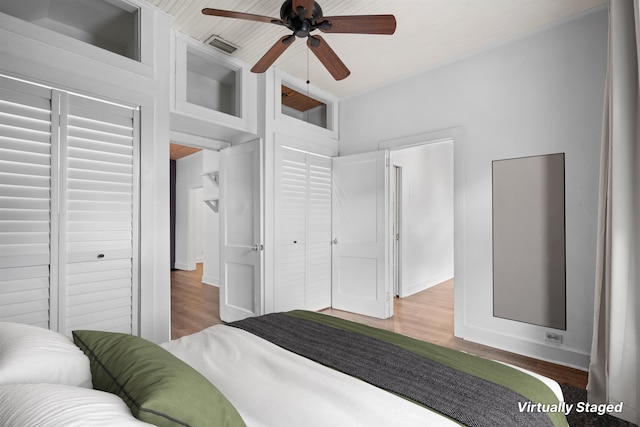 bedroom with a ceiling fan, wood finished floors, and visible vents