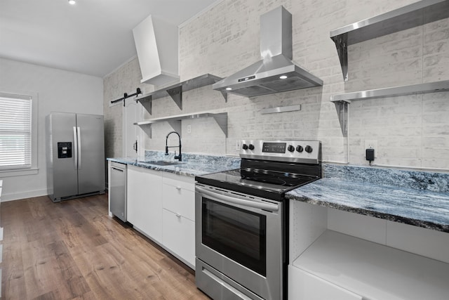 kitchen featuring wall chimney exhaust hood, stainless steel appliances, a sink, backsplash, and open shelves
