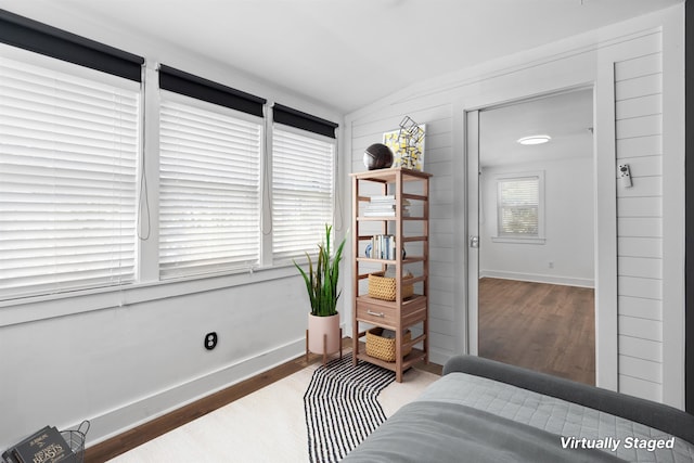 living area featuring lofted ceiling, baseboards, and wood finished floors