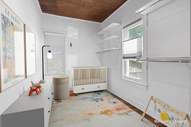 bedroom with wood finished floors, wooden ceiling, baseboards, and crown molding