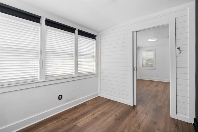 empty room with lofted ceiling, baseboards, and dark wood-type flooring