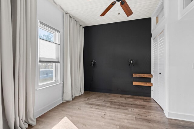 spare room with wood finished floors, a ceiling fan, and baseboards