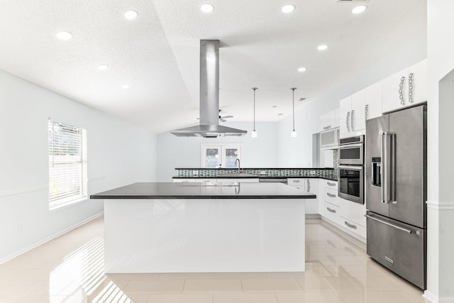 kitchen with kitchen peninsula, appliances with stainless steel finishes, island exhaust hood, white cabinets, and hanging light fixtures