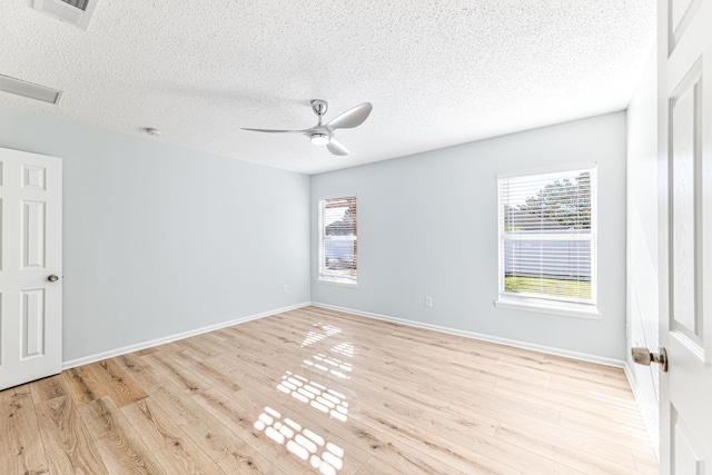 empty room with a textured ceiling, light hardwood / wood-style flooring, plenty of natural light, and ceiling fan