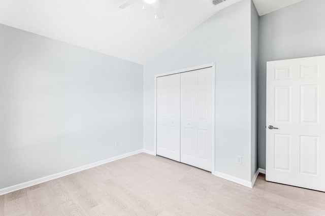 unfurnished bedroom with lofted ceiling, light hardwood / wood-style flooring, ceiling fan, a textured ceiling, and a closet