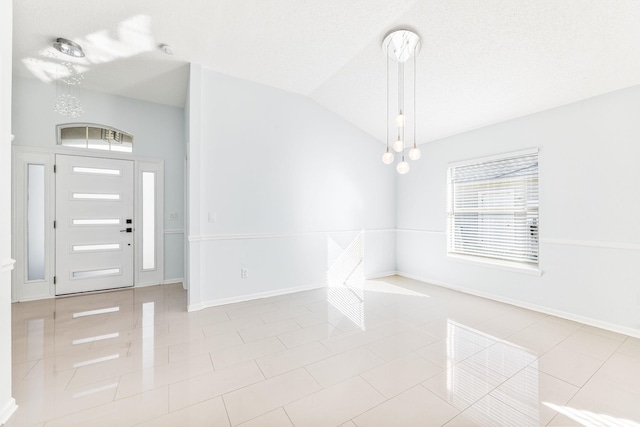 tiled foyer entrance with a textured ceiling and lofted ceiling