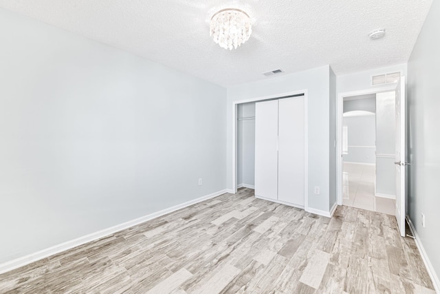 unfurnished bedroom featuring a closet, light hardwood / wood-style flooring, and a textured ceiling