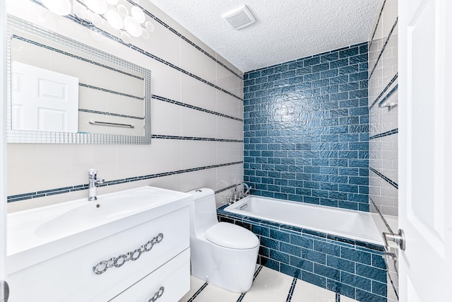 full bathroom with tiled shower / bath combo, a textured ceiling, toilet, vanity, and tile walls