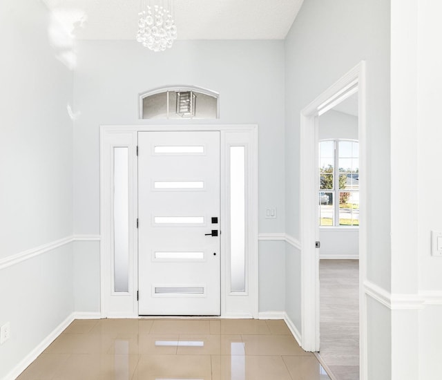 entrance foyer with light tile patterned floors, a chandelier, and a textured ceiling