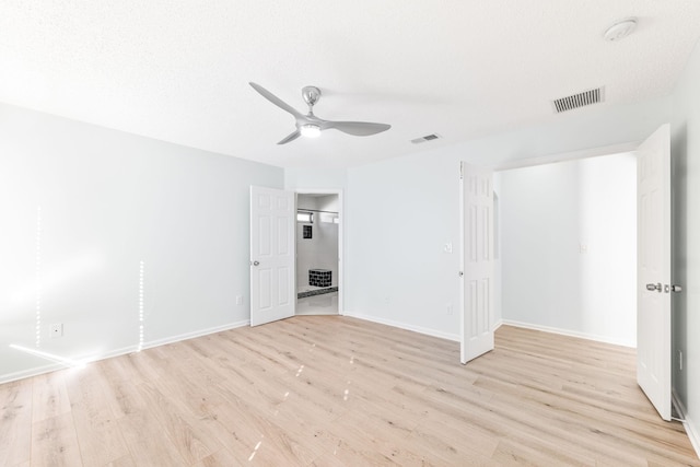 empty room featuring ceiling fan, light hardwood / wood-style floors, and a textured ceiling