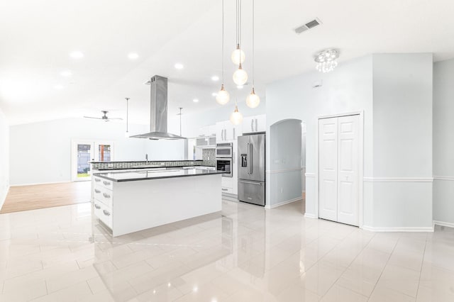 kitchen with high quality fridge, wall chimney exhaust hood, a center island, white cabinetry, and hanging light fixtures