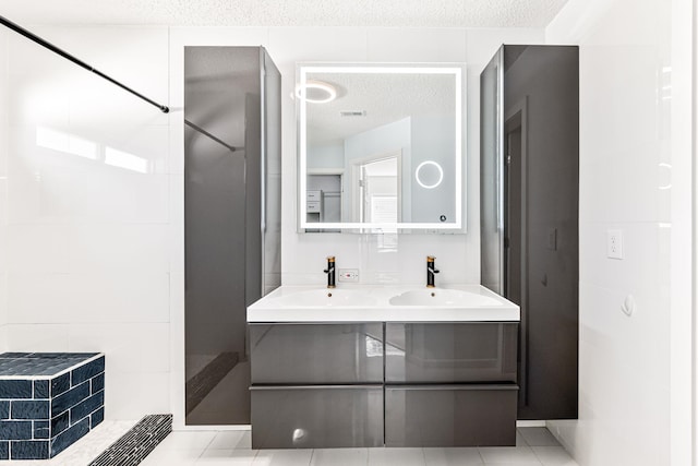 bathroom featuring a shower, tile patterned flooring, vanity, and a textured ceiling