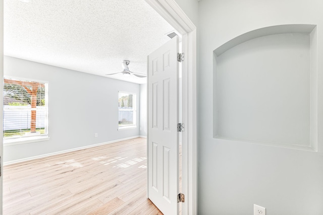 hallway with a textured ceiling and light wood-type flooring